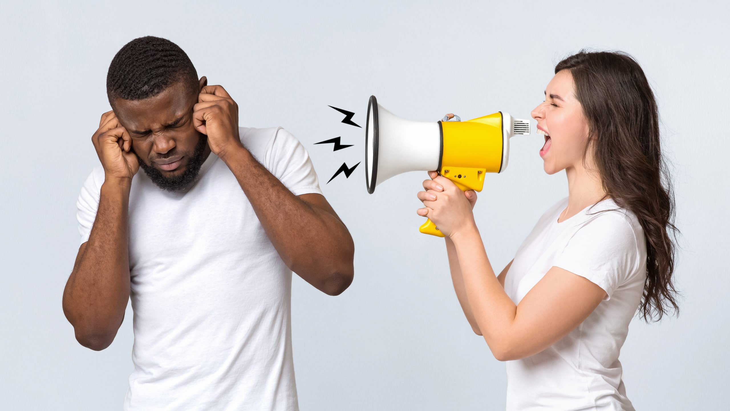 Angry Woman Shouting At Her Boyfriend With Loudspeaker Over Light Background